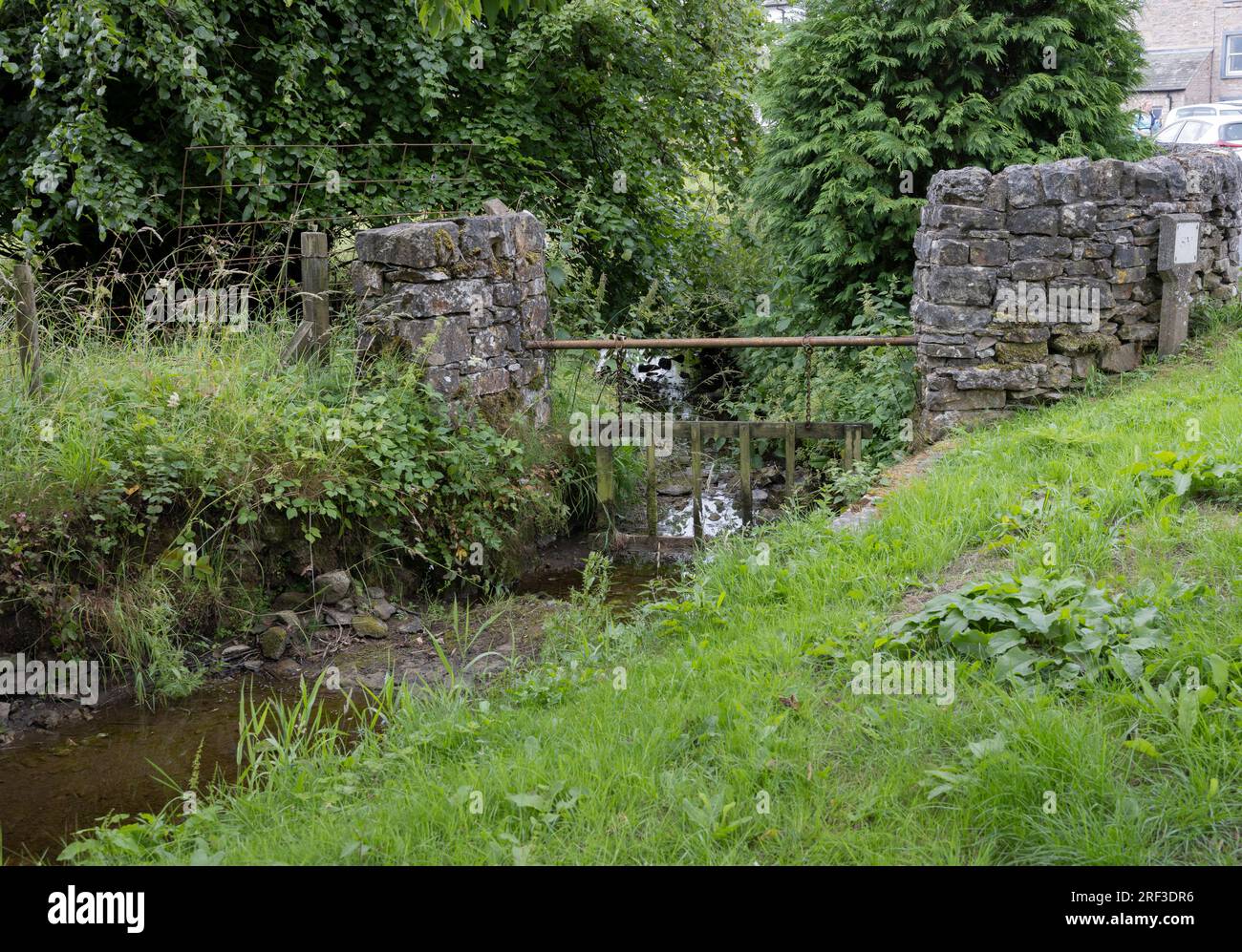 Dry stone wall and gratings over the small beck running through Orton in Westmoreland Stock Photo