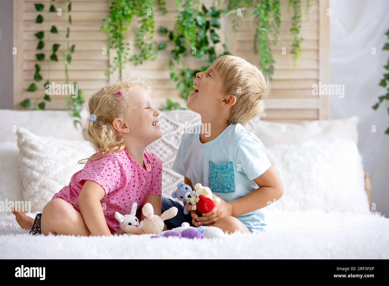 Cute sweet toddler children, tickling feet on the bed, laughing and smiling, childish mischief, happiness and joy Stock Photo