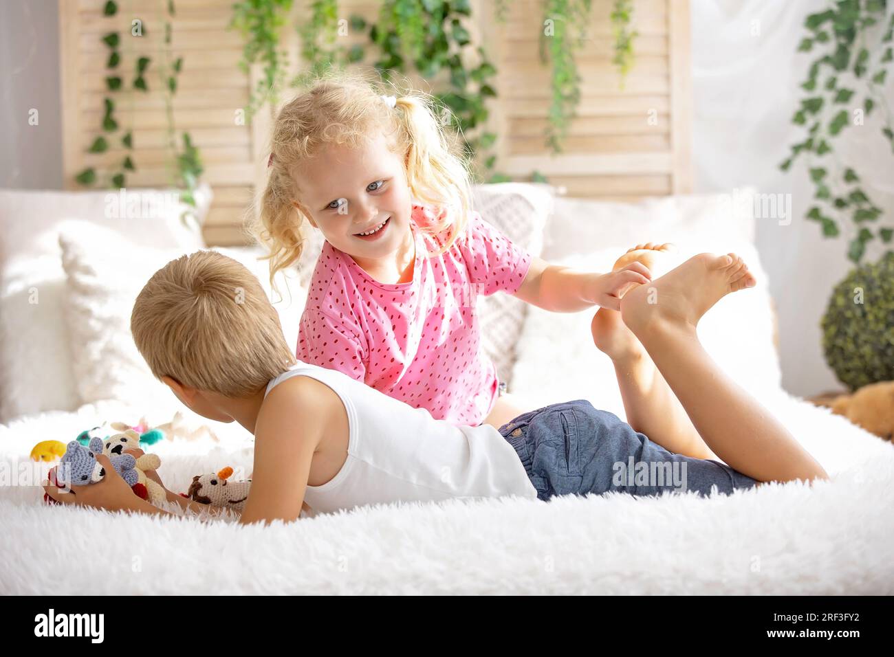 Cute sweet toddler children, tickling feet on the bed, laughing and smiling, childish mischief, happiness and joy Stock Photo