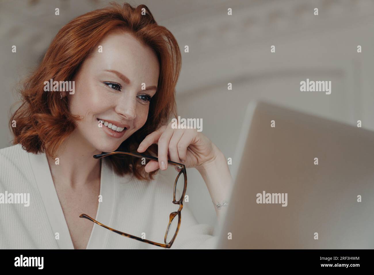 Happy ginger web designer, creates projects, researches, and browses online, using a laptop and spectacles. Stock Photo