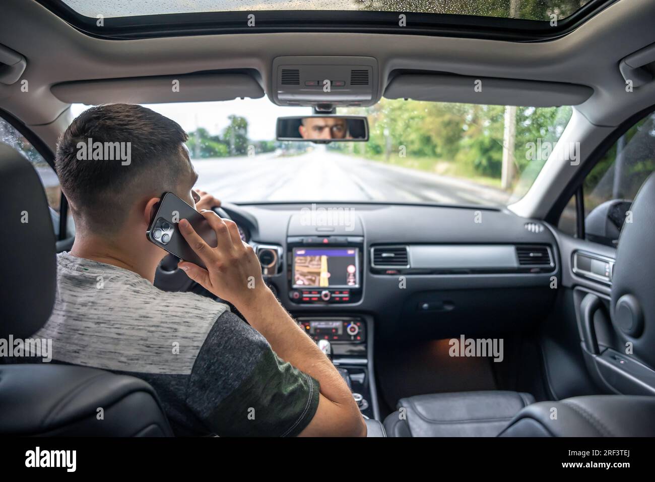 Businessman talking on cell phone while driving. Stock Photo