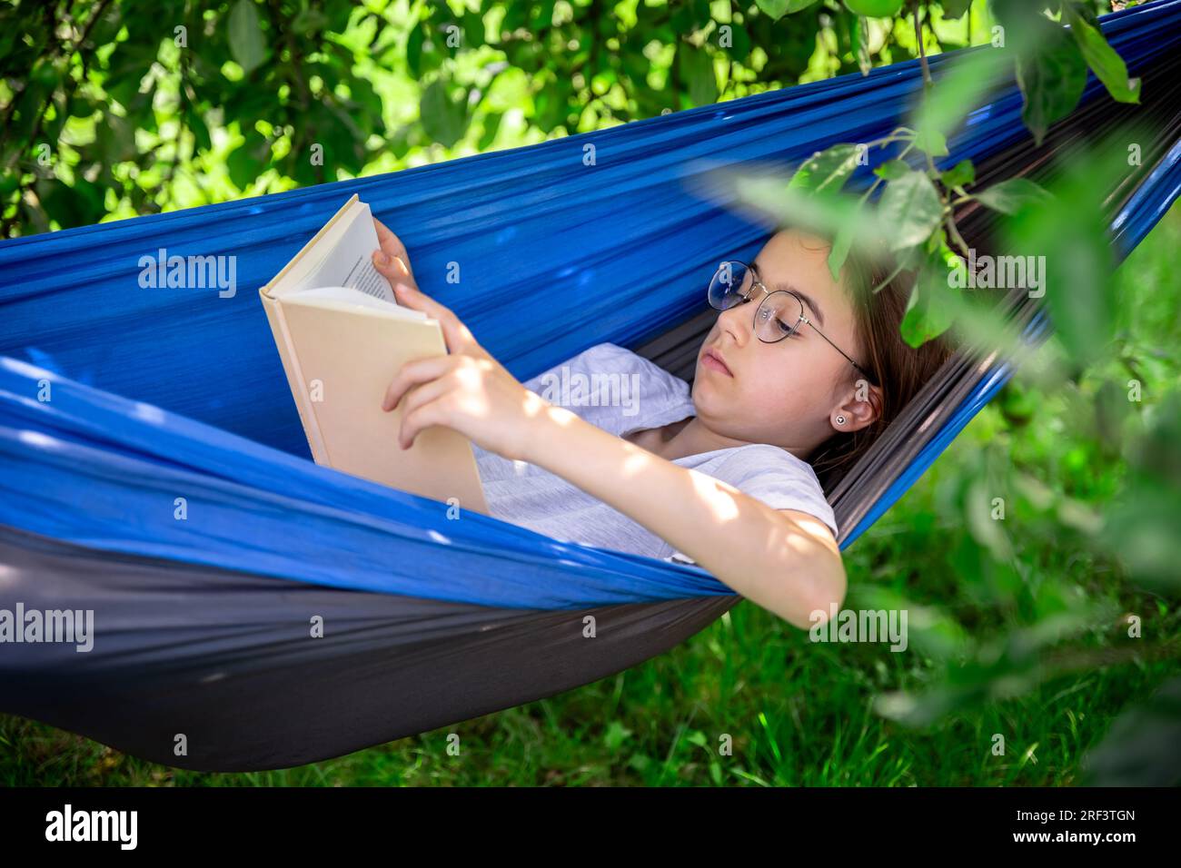 Cute girl reading a book in a hammock in the garden Stock Photo - Alamy