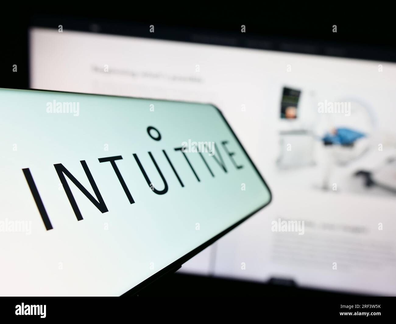 Smartphone with logo of American medical company Intuitive Surgical Inc. on screen in front of business website. Focus on left of phone display. Stock Photo