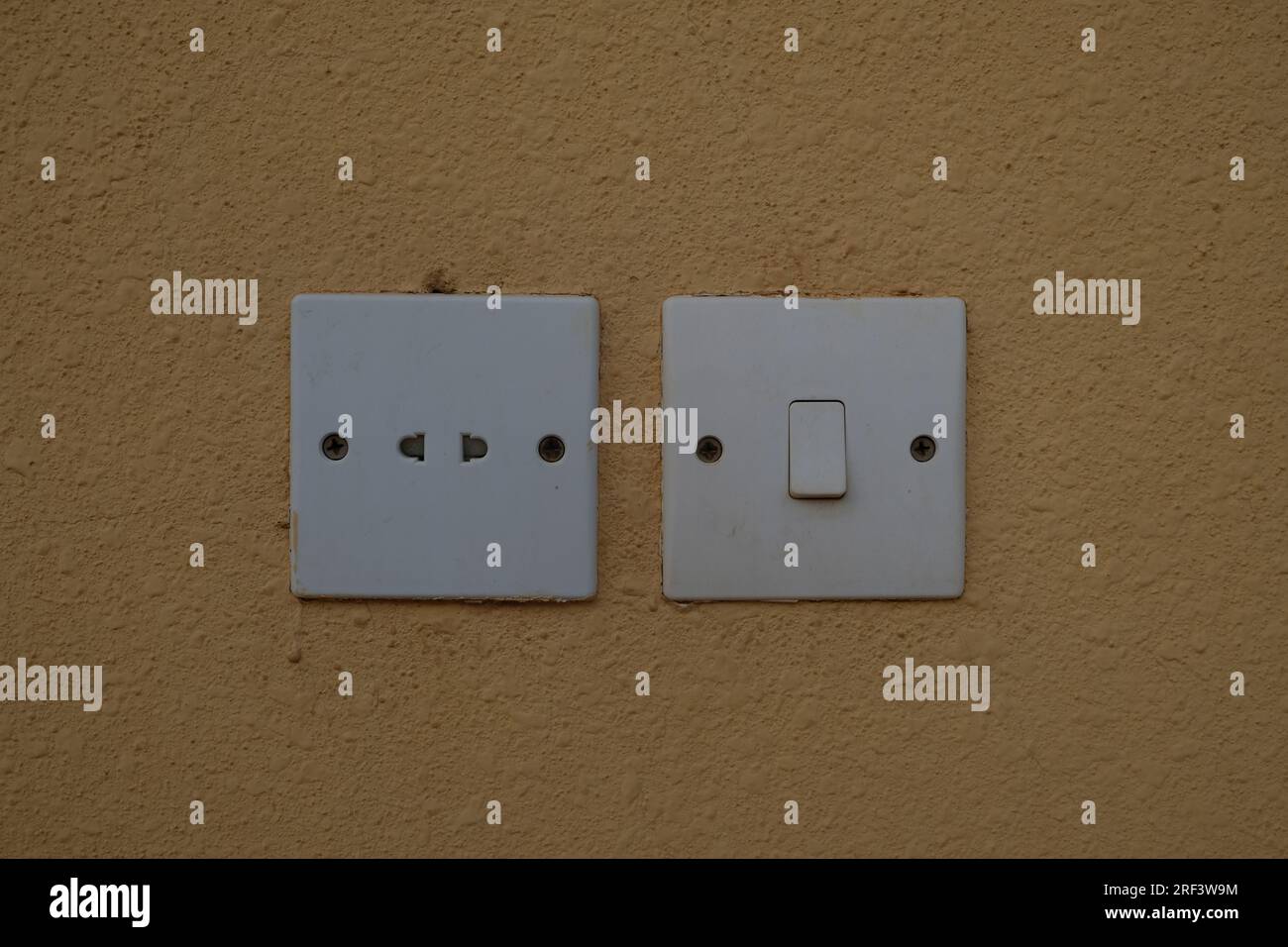Electric Plug and Electric Switch on Dark Yellow Painted Wall Stock