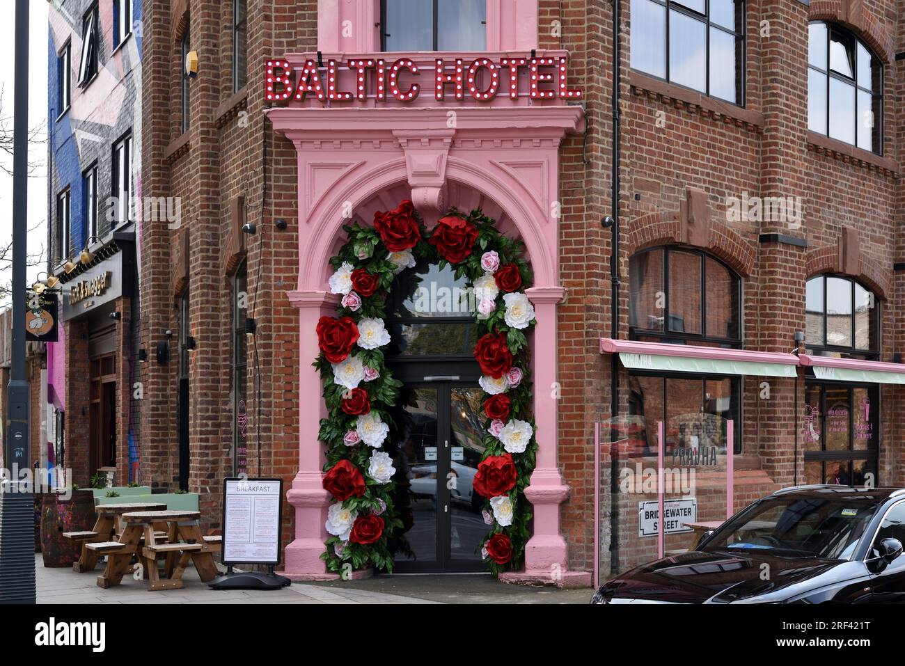 Kitsch Pink Entrance Door and  Artificial Decorative or Plastic Flowers of Baltic Hotel in the Baltic Triangle Area of Liverpool England UK Stock Photo