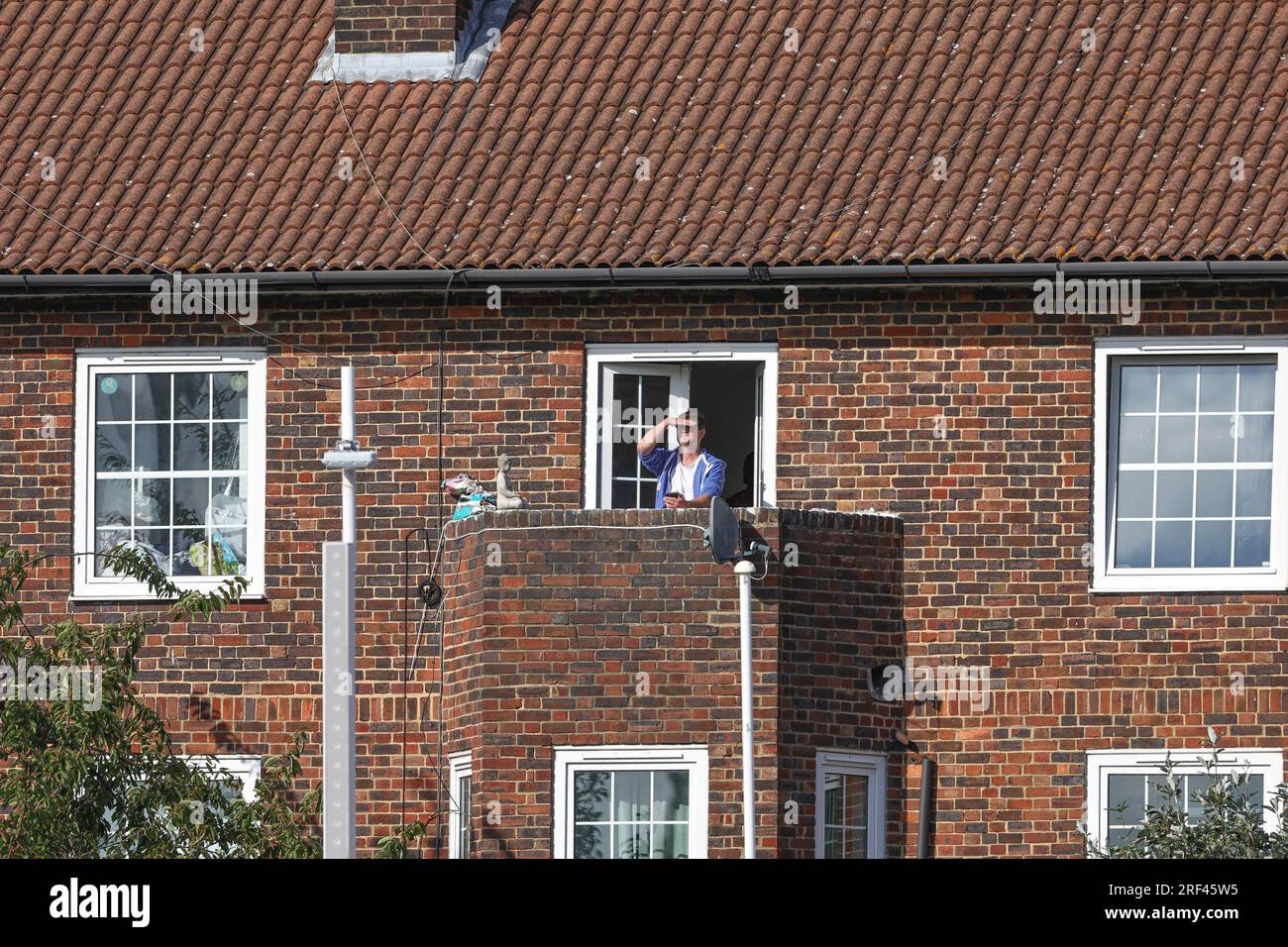 A person watches the cricket from a balcony of a house just behind the ground during the LV= Insurance Ashes Fifth Test Series Day Five England v Australia at The Kia Oval, London, United Kingdom, 31st July 2023  (Photo by Mark Cosgrove/News Images) Stock Photo