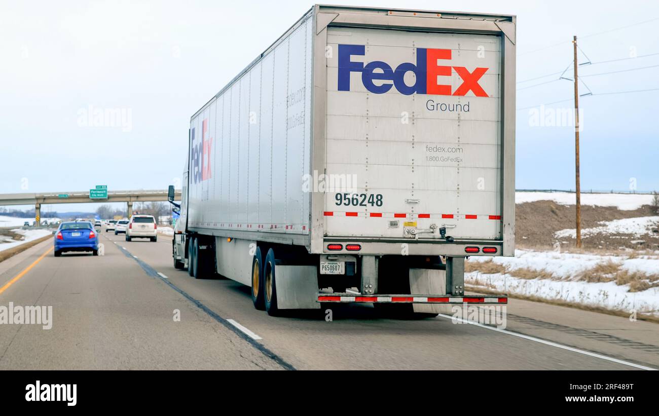 FARIBAULT, MN - 5 MAR 2023: Fed Ex Semi Truck Driving On Freeway, viewed through a car windshield on a Cloudy Day. Stock Photo