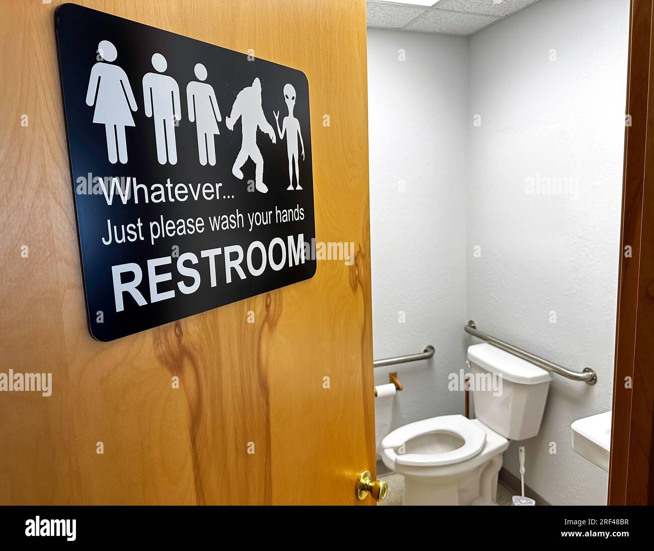 Open Toilet Door of Public Restroom with a Gender Inclusive Sign. Stock Photo