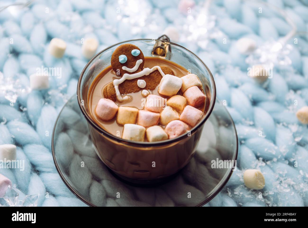 Gingerbread man soaking in a cup of hot chocolate with marshmallows, cozy winter setting in home. Stock Photo