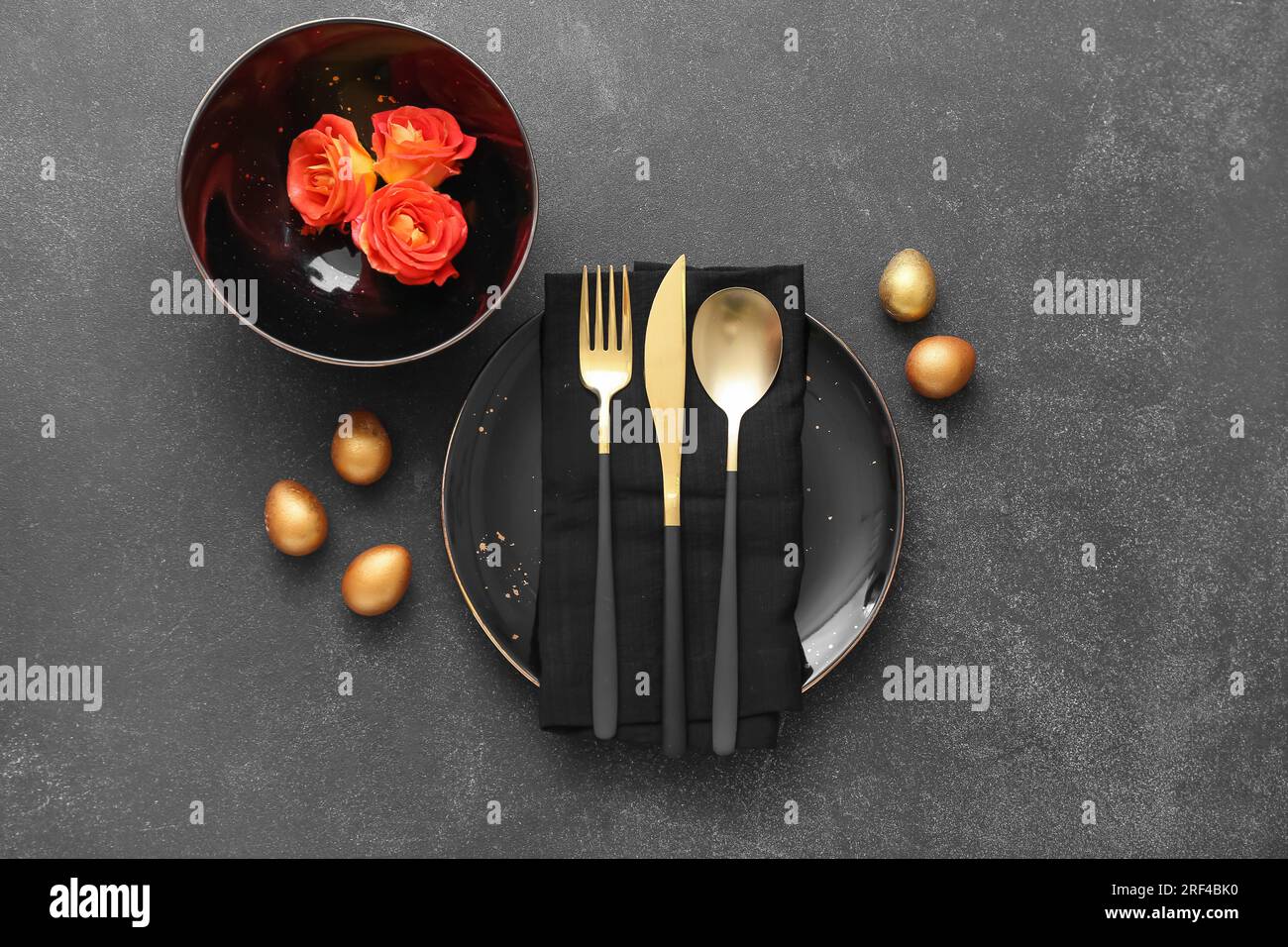 Table setting with Easter eggs and roses on dark background Stock Photo