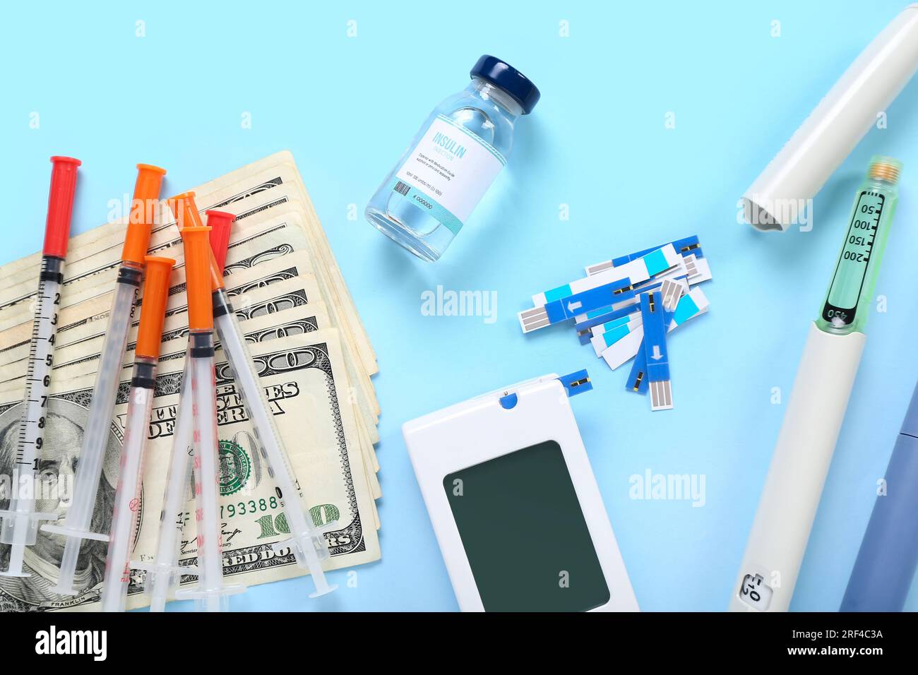 Insulin with lancet pens, syringes and money on blue