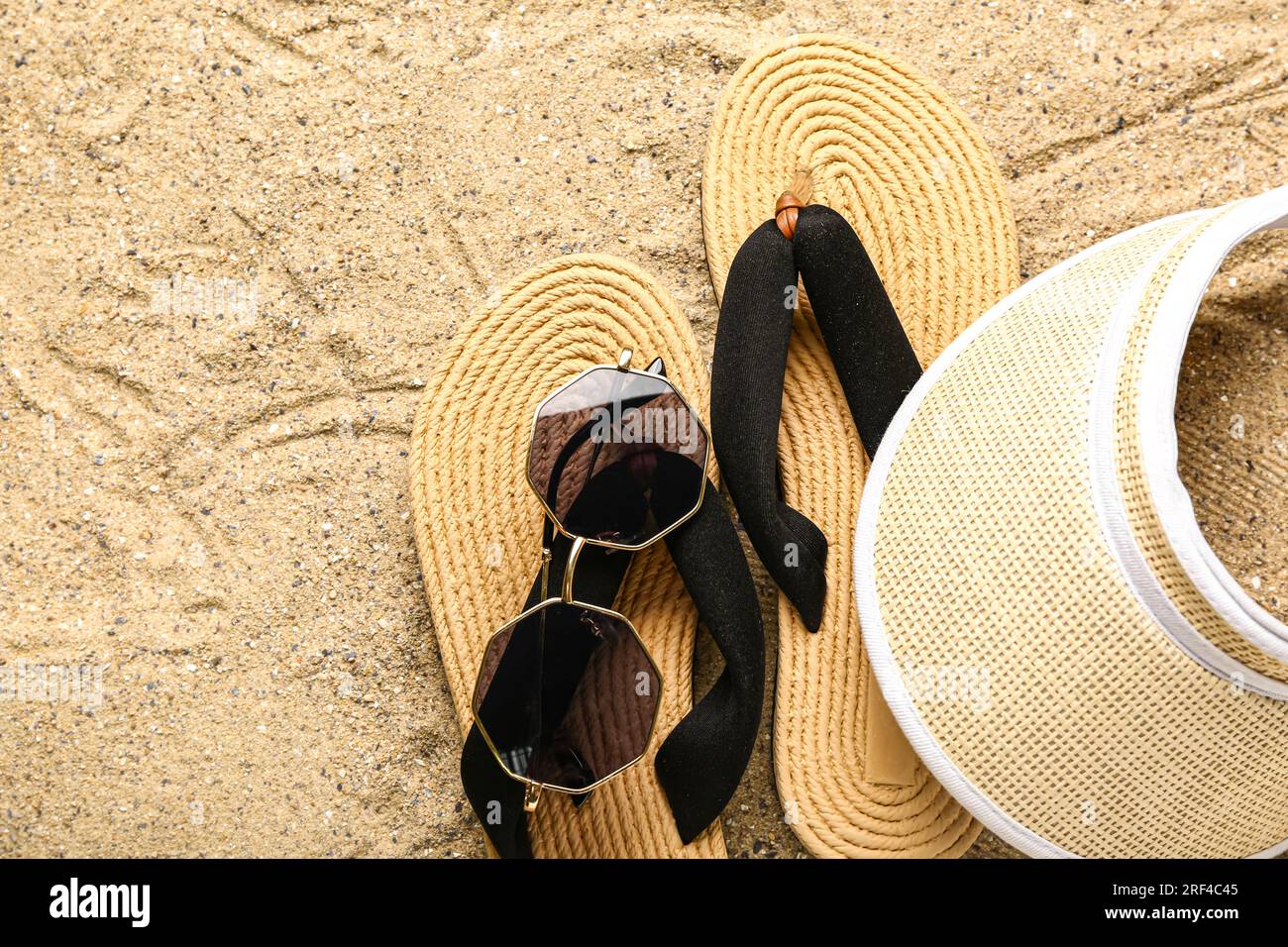 Flip-flops with sunglasses and cap on sand Stock Photo - Alamy