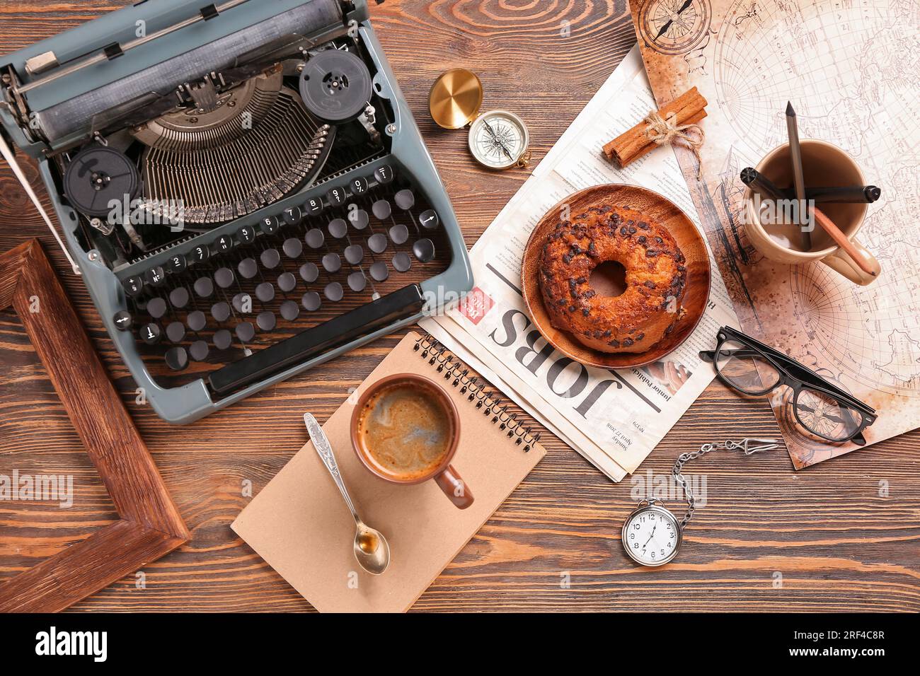 Cup of coffee with notebook, typewriter, newspaper, bun and map on wooden background Stock Photo