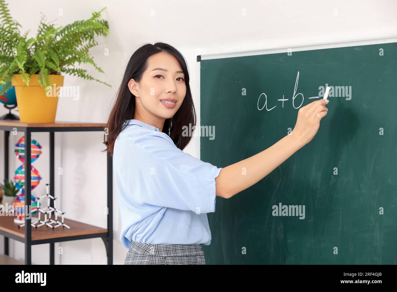 Female Asian teacher conducting Math near chalkboard in classroom Stock ...