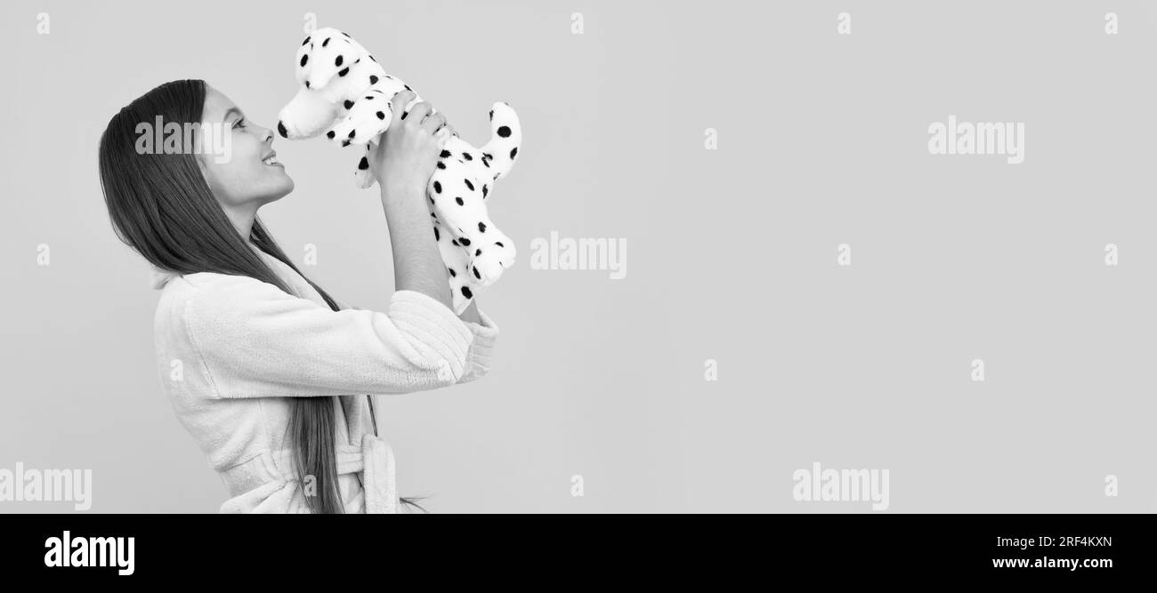 happy teen girl in home terry bathrobe with toy, kiss. Banner of child girl with toy, studio portrait, header with copy space. Stock Photo