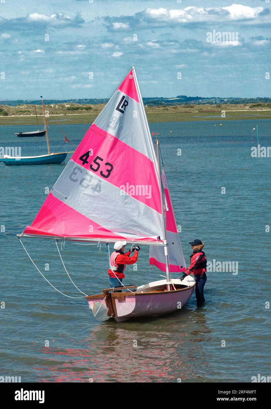 Two women sailors preparing a Lymington River scow to go sailing at West Wittering, near Chichester, West  Sussex, England, UK Stock Photo