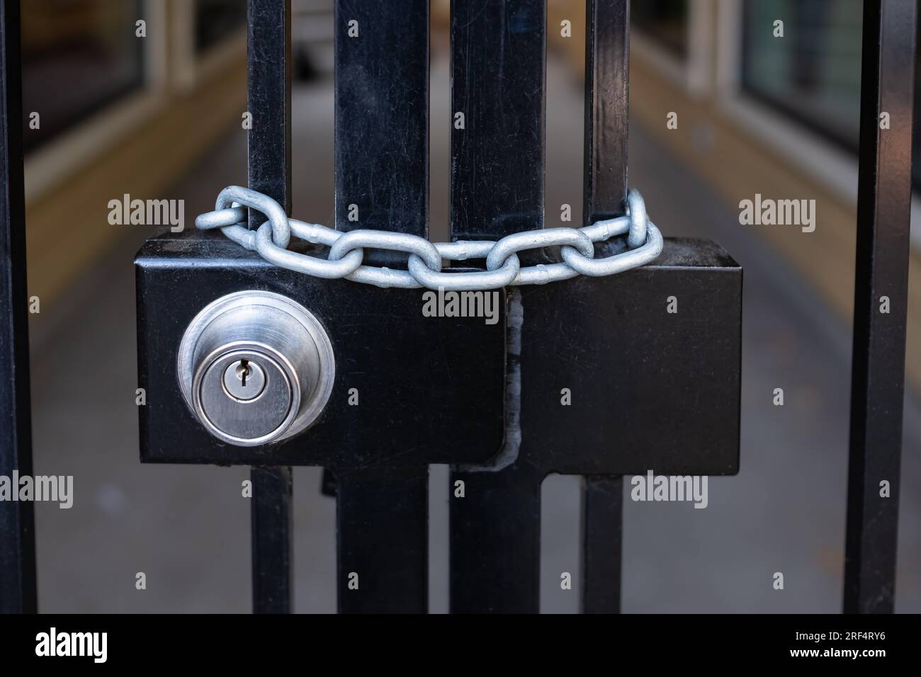 Lock and strong steel chain wrapped around the metal entrance gate