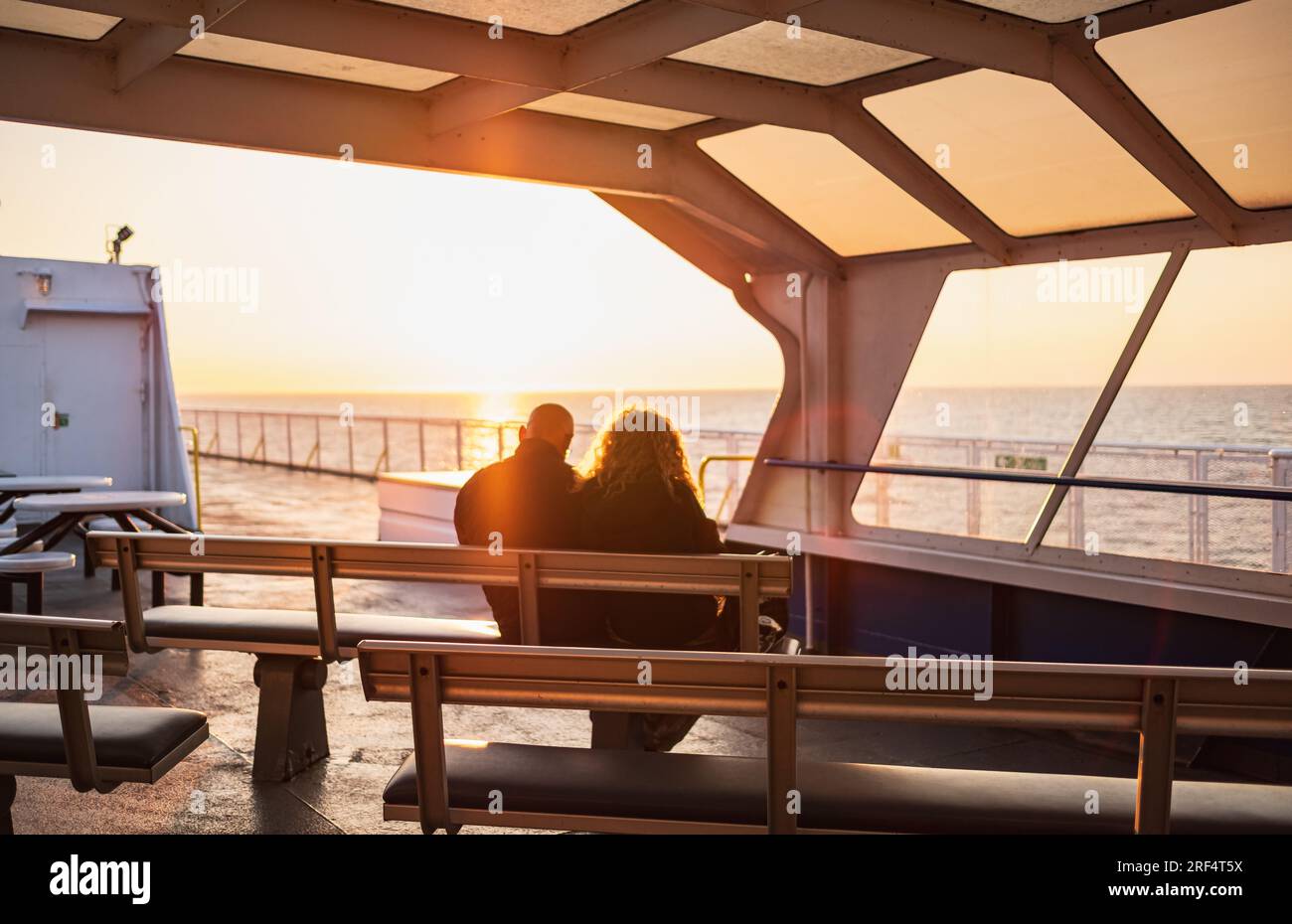 Silhouette couple are watching sunset together on a cruise liner. Blur Senior Couple Watching the Sunrise Together on a ship. Elderly man and woman si Stock Photo
