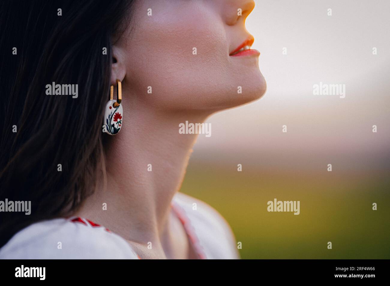 Young woman with ethnic earring and shirt with traditional ornaments breath free Stock Photo