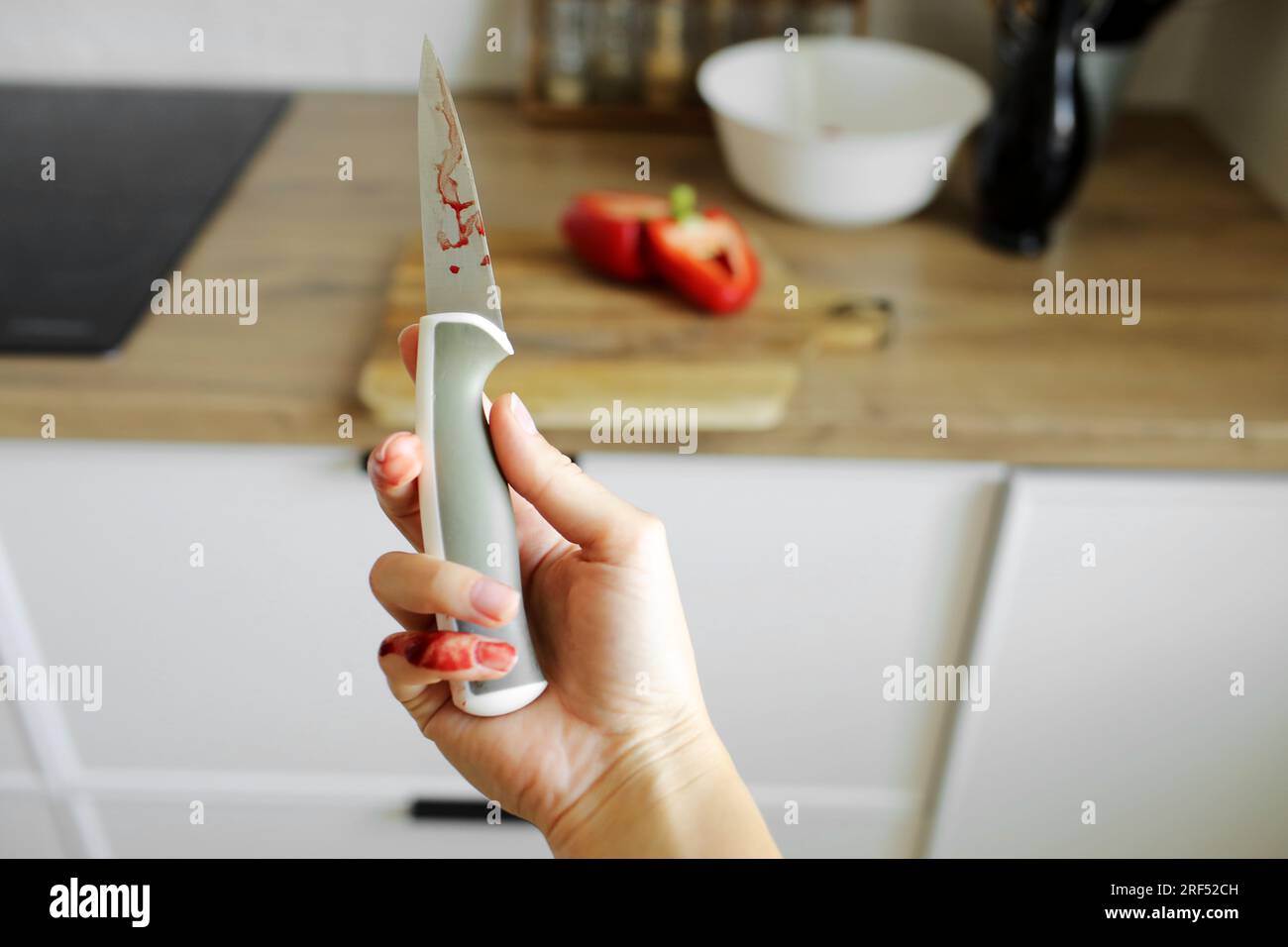 Woman cut her little finger with a knife while cooking vegetable salad ...