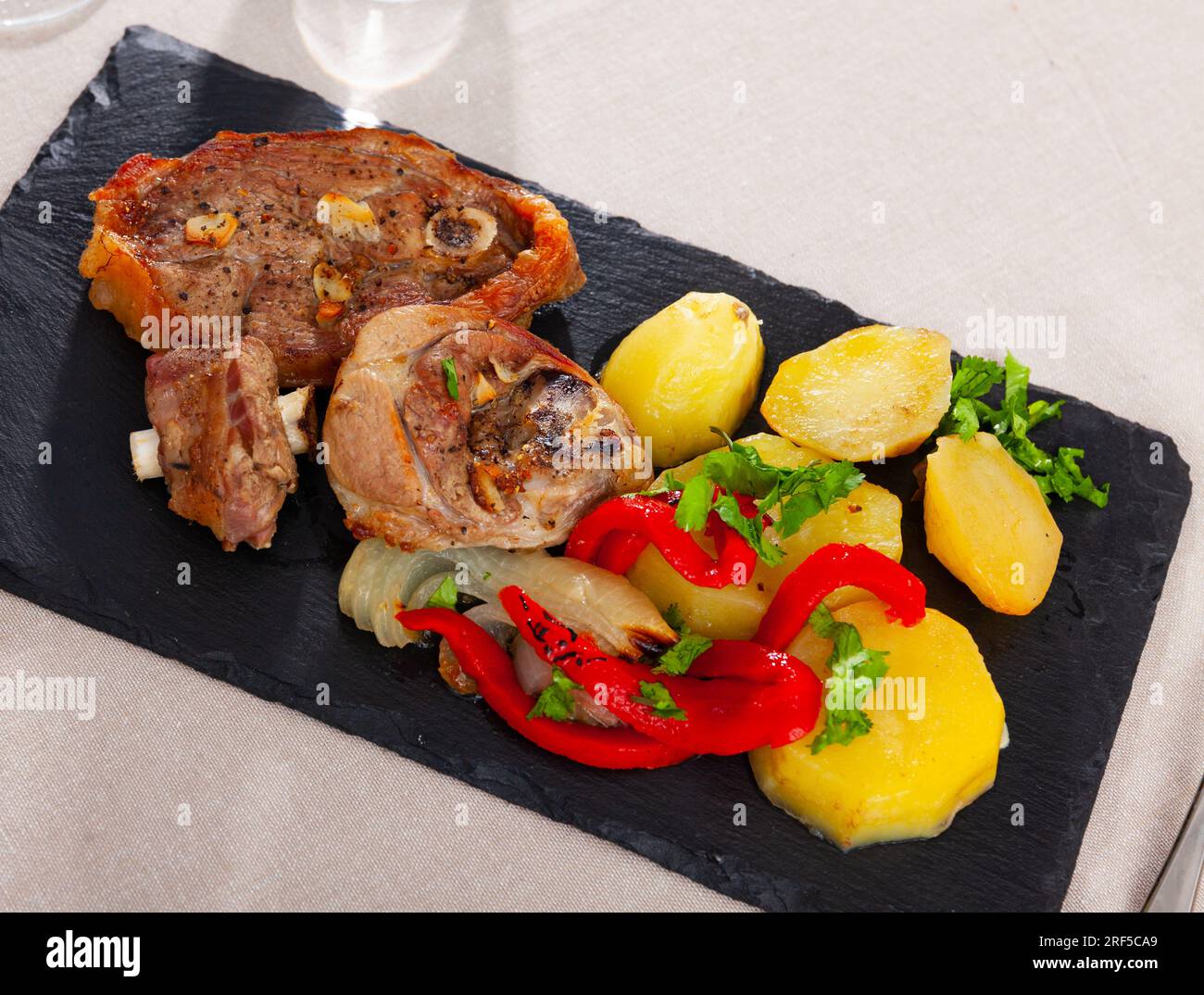 Portion of roasted lamb leg with potatoes and pepper Stock Photo - Alamy