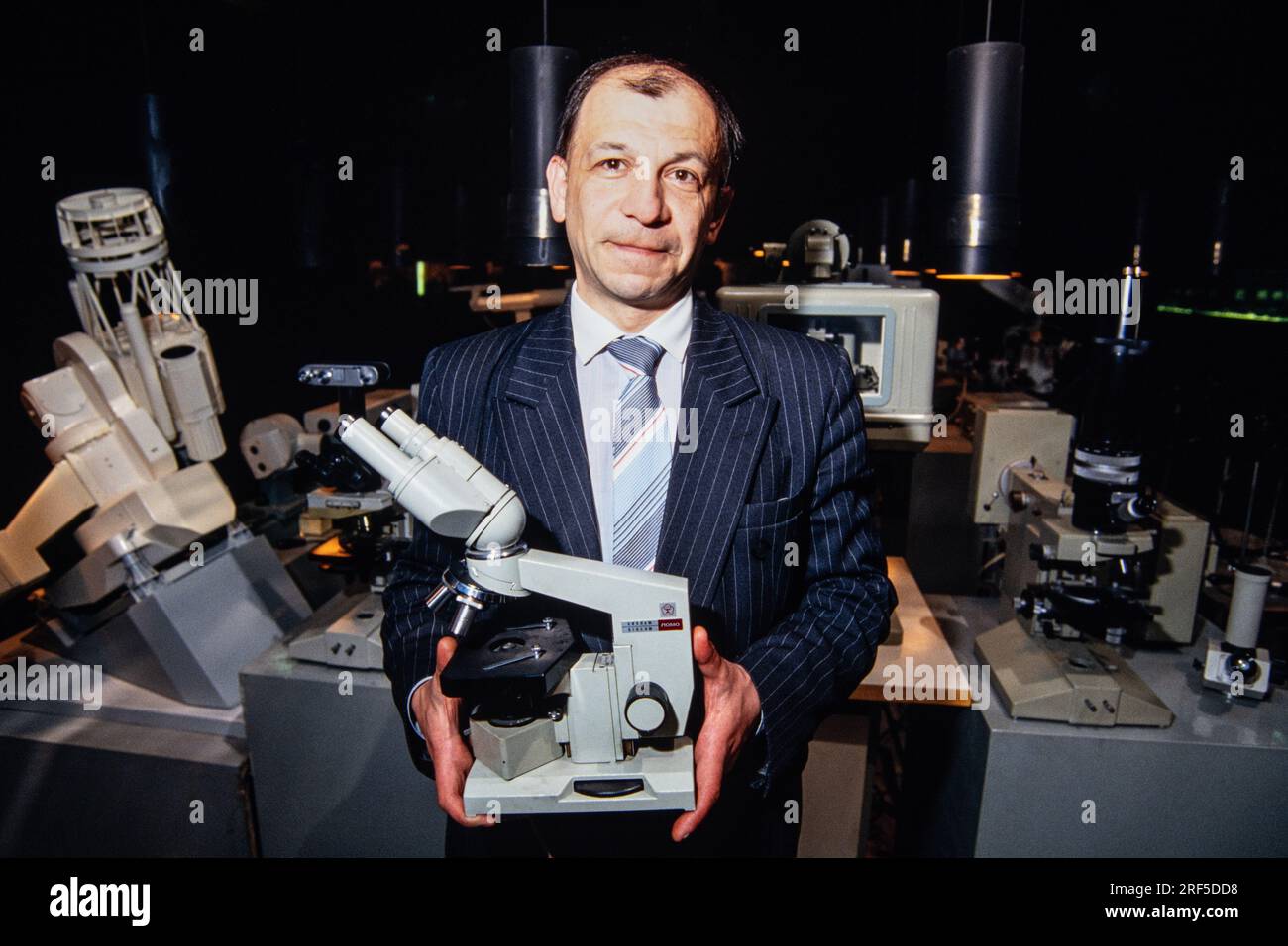 Head of business development and chief economist Vladimir Didyk holds an optical microscope produced at LOMO Optical Factory, December 10, 1994 in St. Petersburg, Russia. The Leningrad Optical Mechanical Association begun production in 1914 under the Soviet Union and was privatized in 1994 specializing in cameras, telescopes, microscopes and endoscopes. Stock Photo