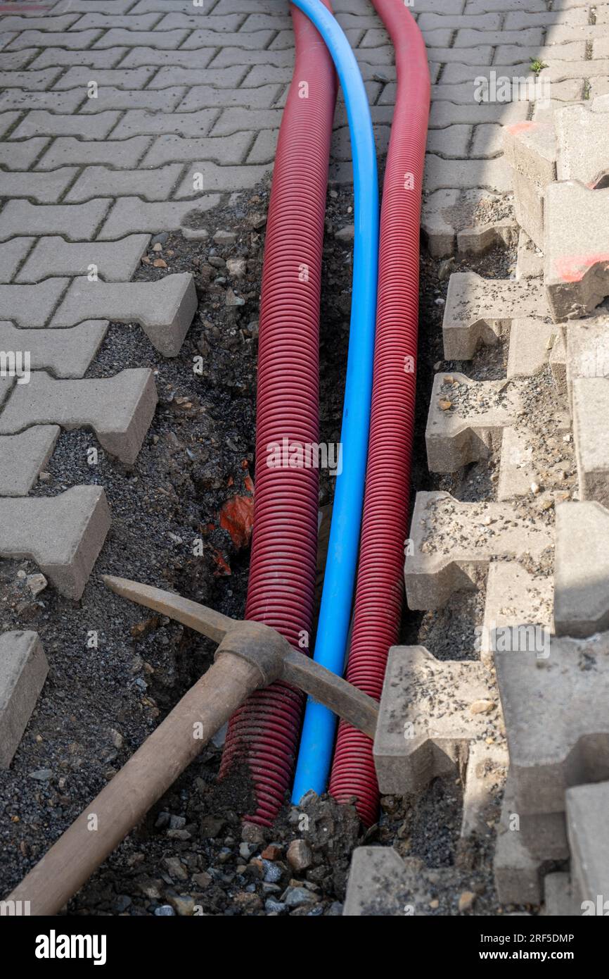 Electric cables in red corrugated pipe are buried underground on the ...