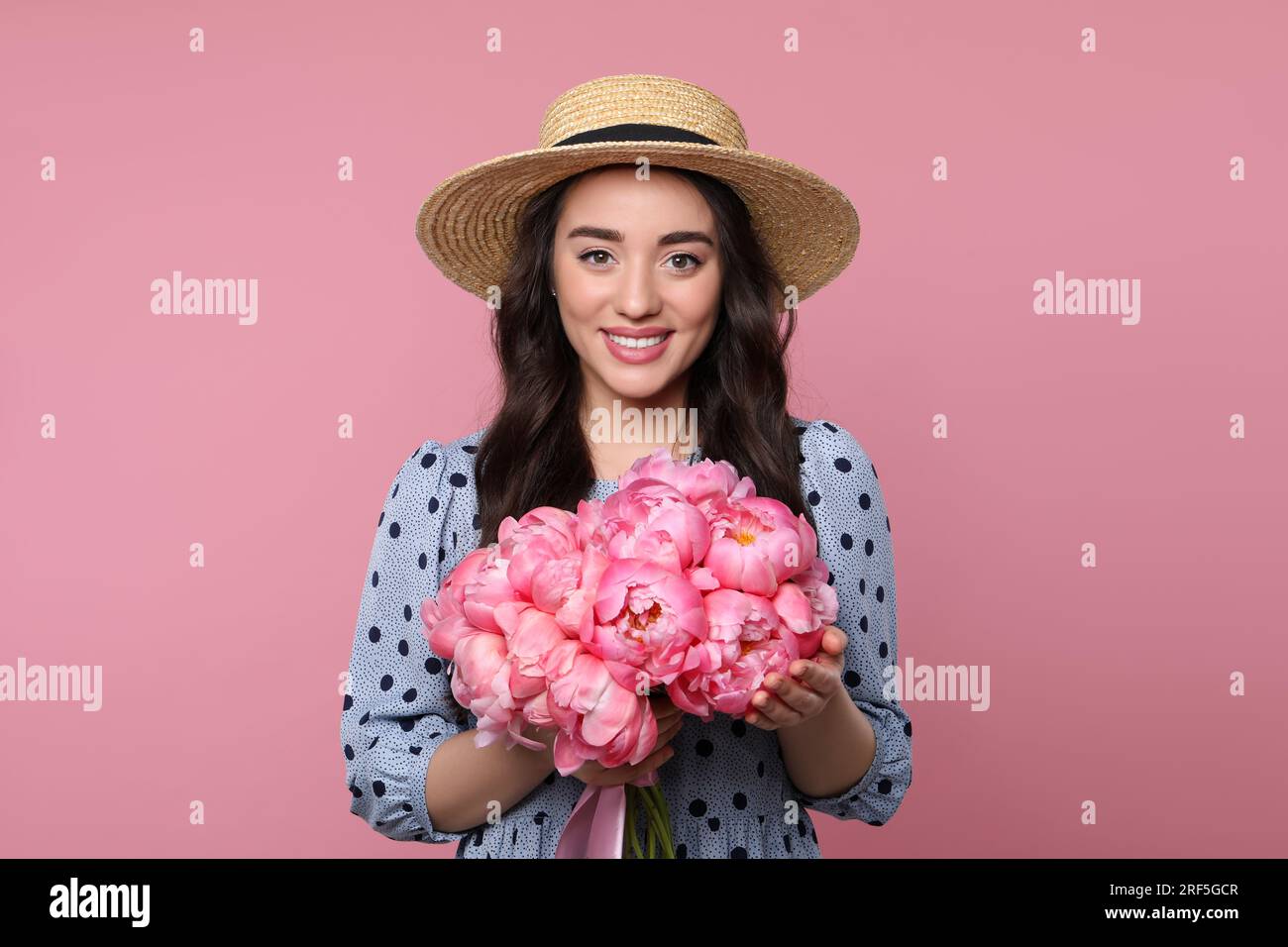 Beautiful young woman in straw hat with bouquet of peonies on pink ...