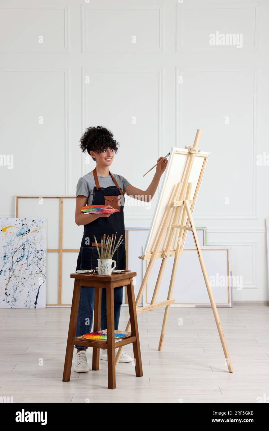 Young woman painting on easel with canvas in studio Stock Photo - Alamy