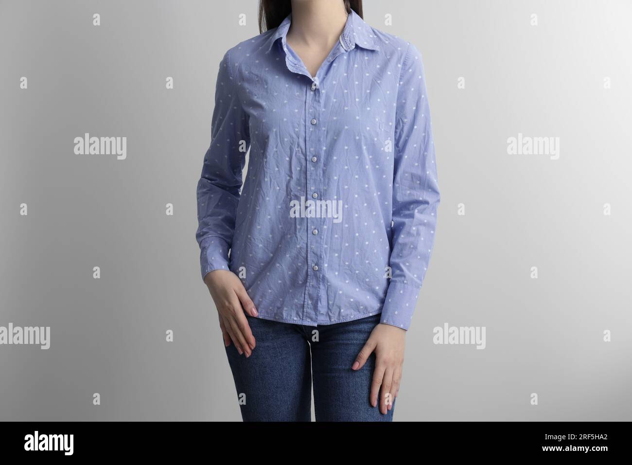 Woman wearing wrinkled light blue polka dot blouse on light grey ...