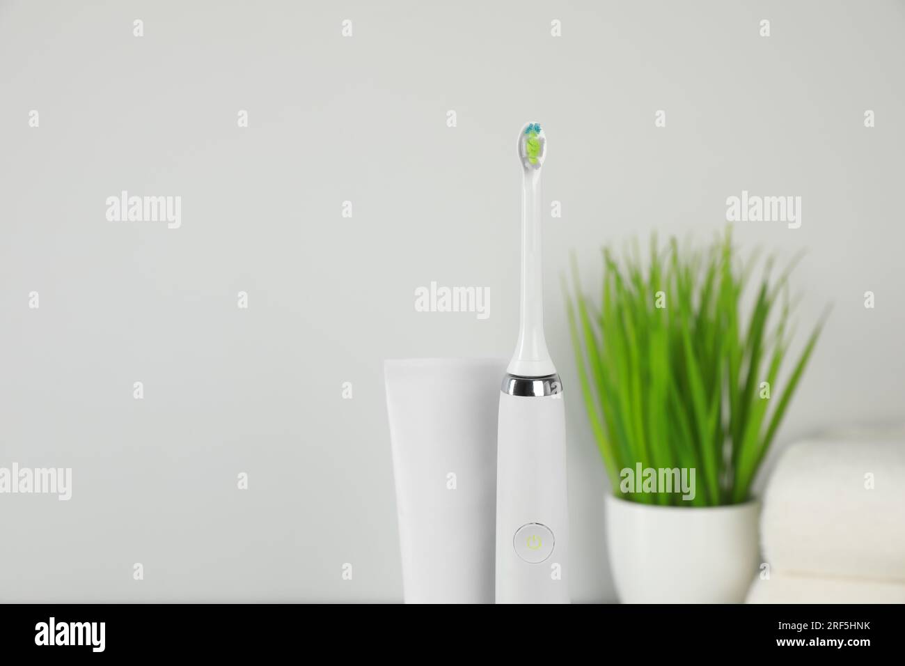 Electric toothbrush and tube with paste on light background Stock Photo