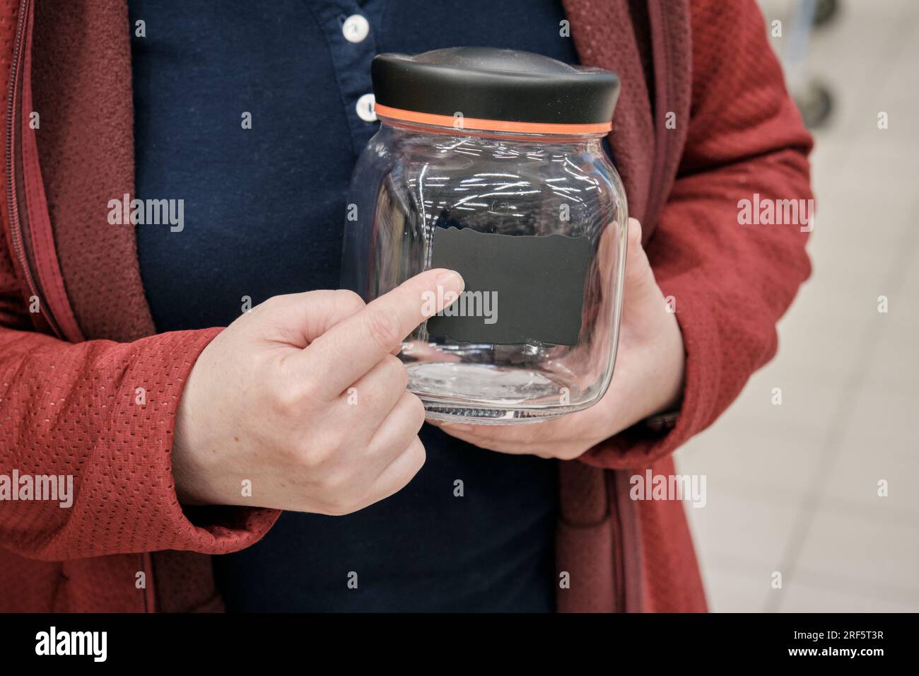 Woman in a store chooses a glass jar for storing spices, flour, cereals