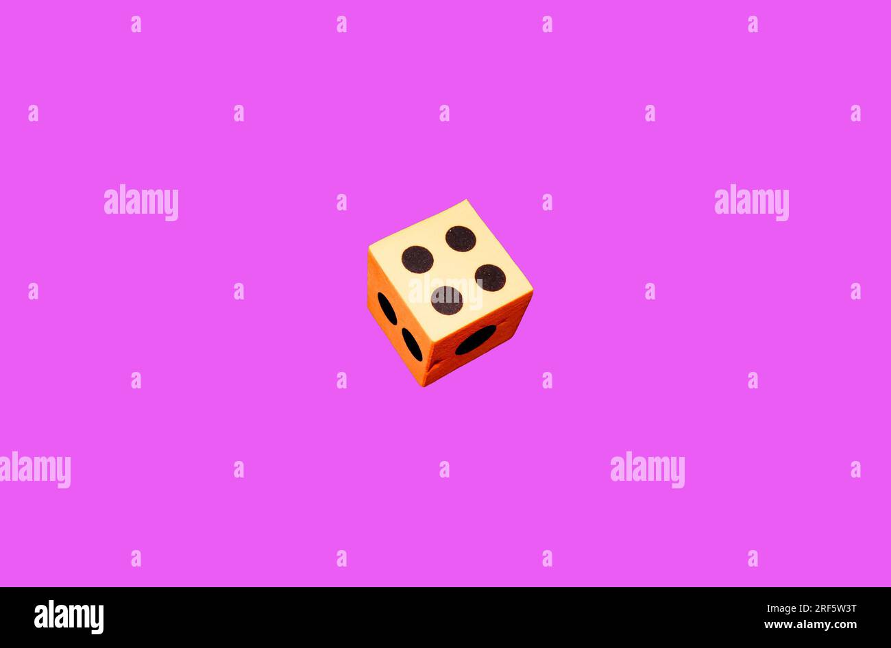 An orange foam dice on a pink background Stock Photo