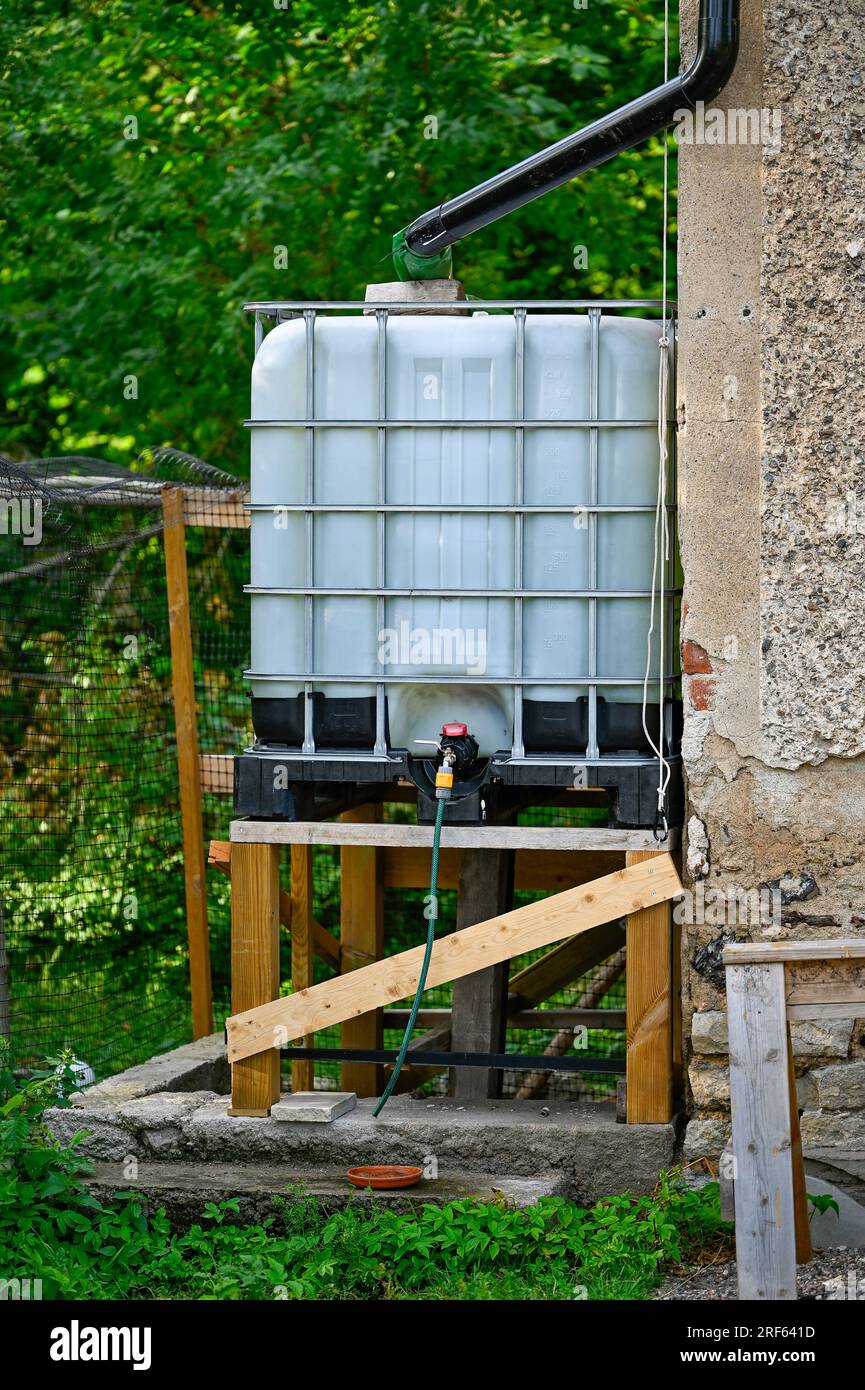 White plastic cubic container collecting rainwater from water pipe