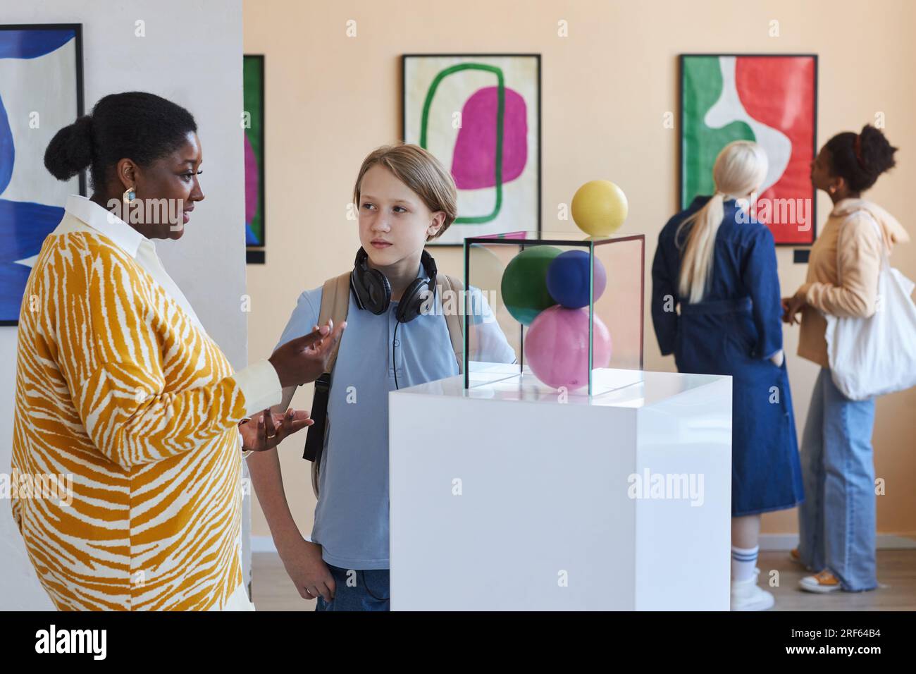 Young black woman explaining modern art to teenage boy in museum, copy space Stock Photo