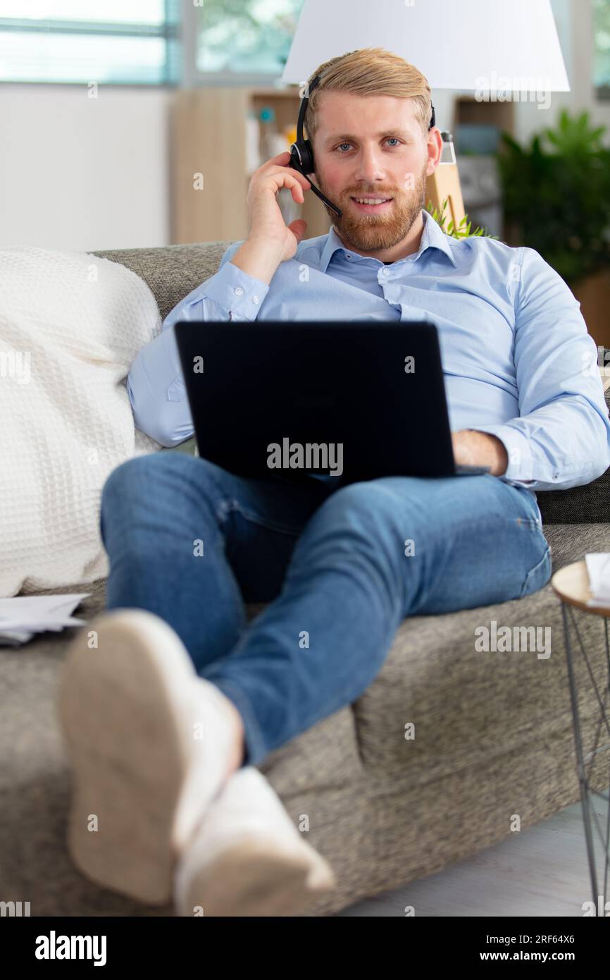 man on couch at home studying using laptop Stock Photo