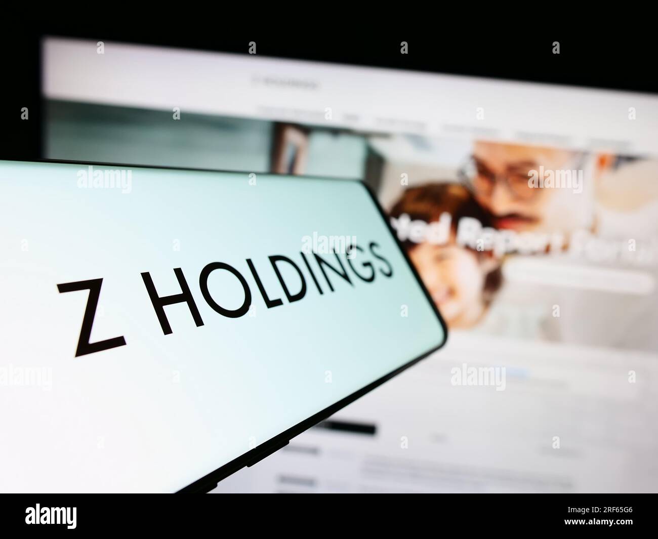 Cellphone with logo of Japanese company Z Holdings Corporation on screen in front of business website. Focus on left of phone display. Stock Photo