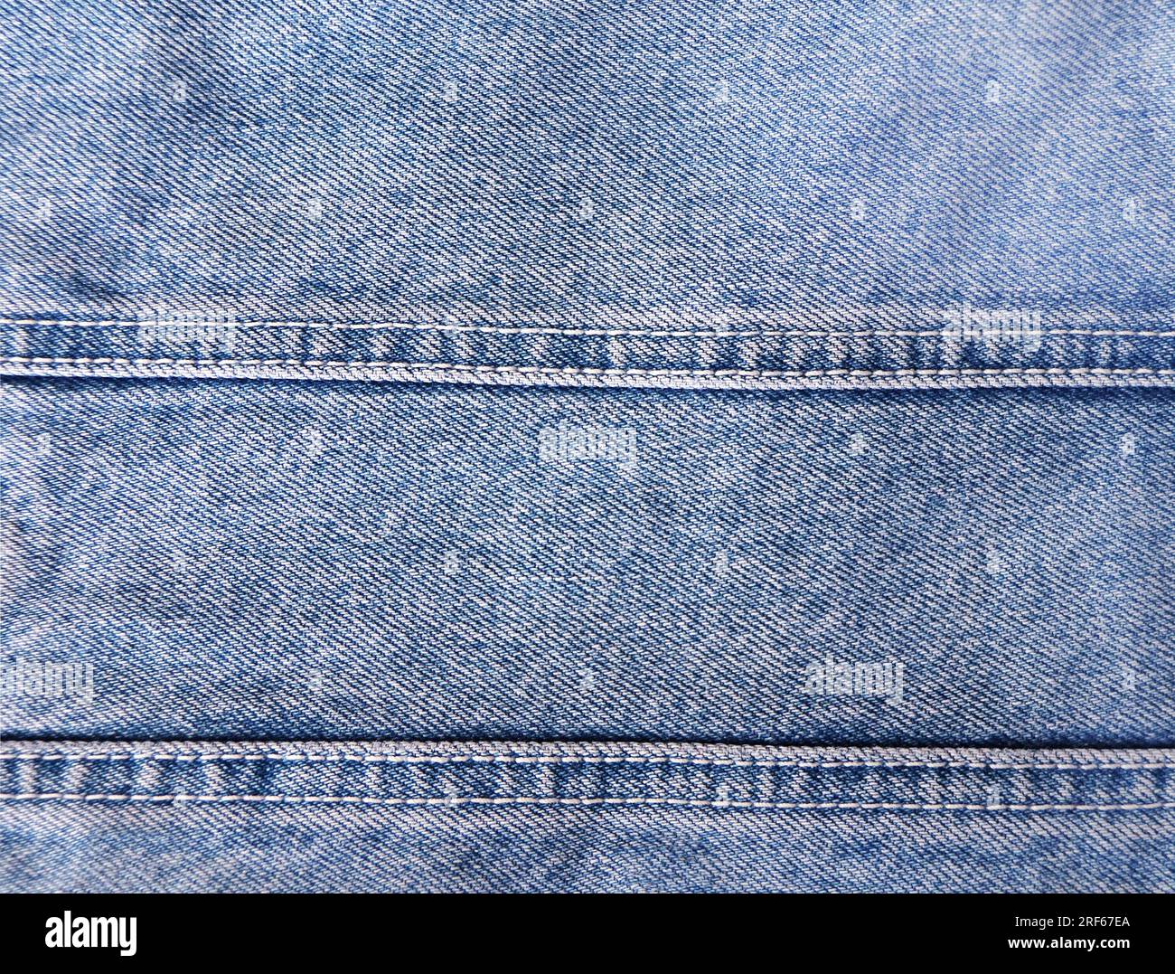 Blue denim background with a seam. Light blue color denim jeans fabric texture. Copy space for text Stock Photo