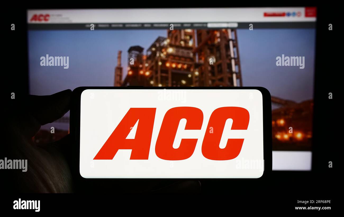 Person holding cellphone with logo of Indian cement company ACC Limited on screen in front of business webpage. Focus on phone display. Stock Photo