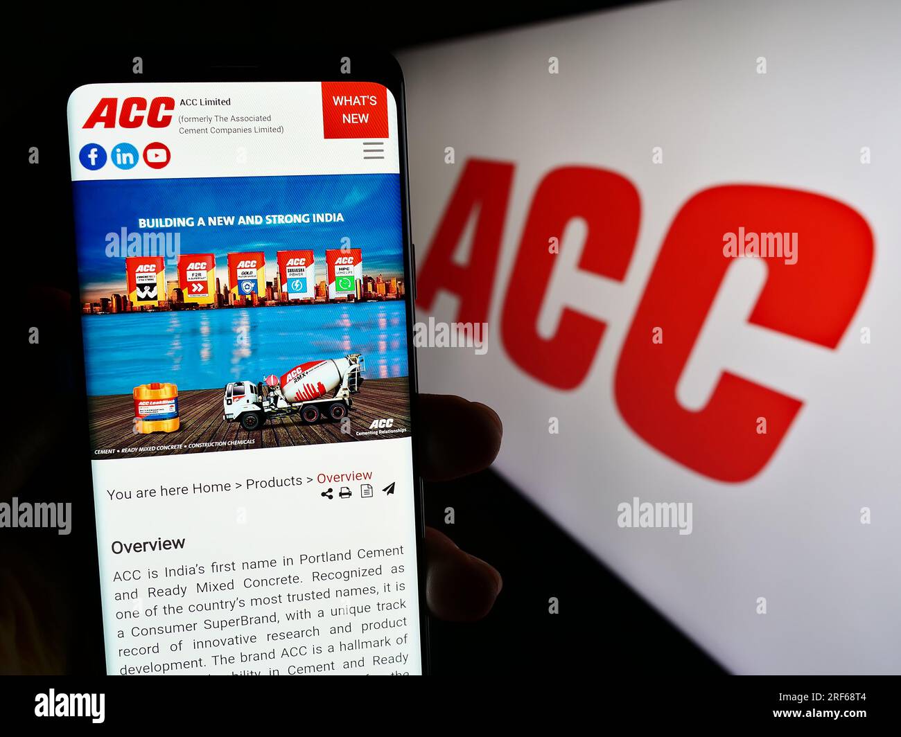 Person holding cellphone with webpage of Indian cement company ACC Limited on screen in front of logo. Focus on center of phone display. Stock Photo