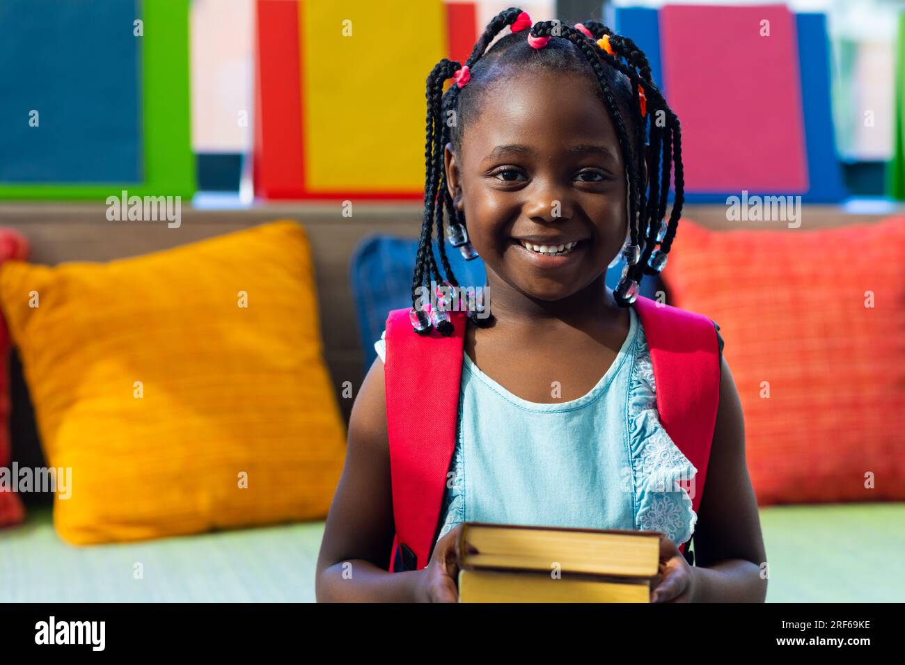 Portrait of happy african american schoolgirl with books in colourful ...