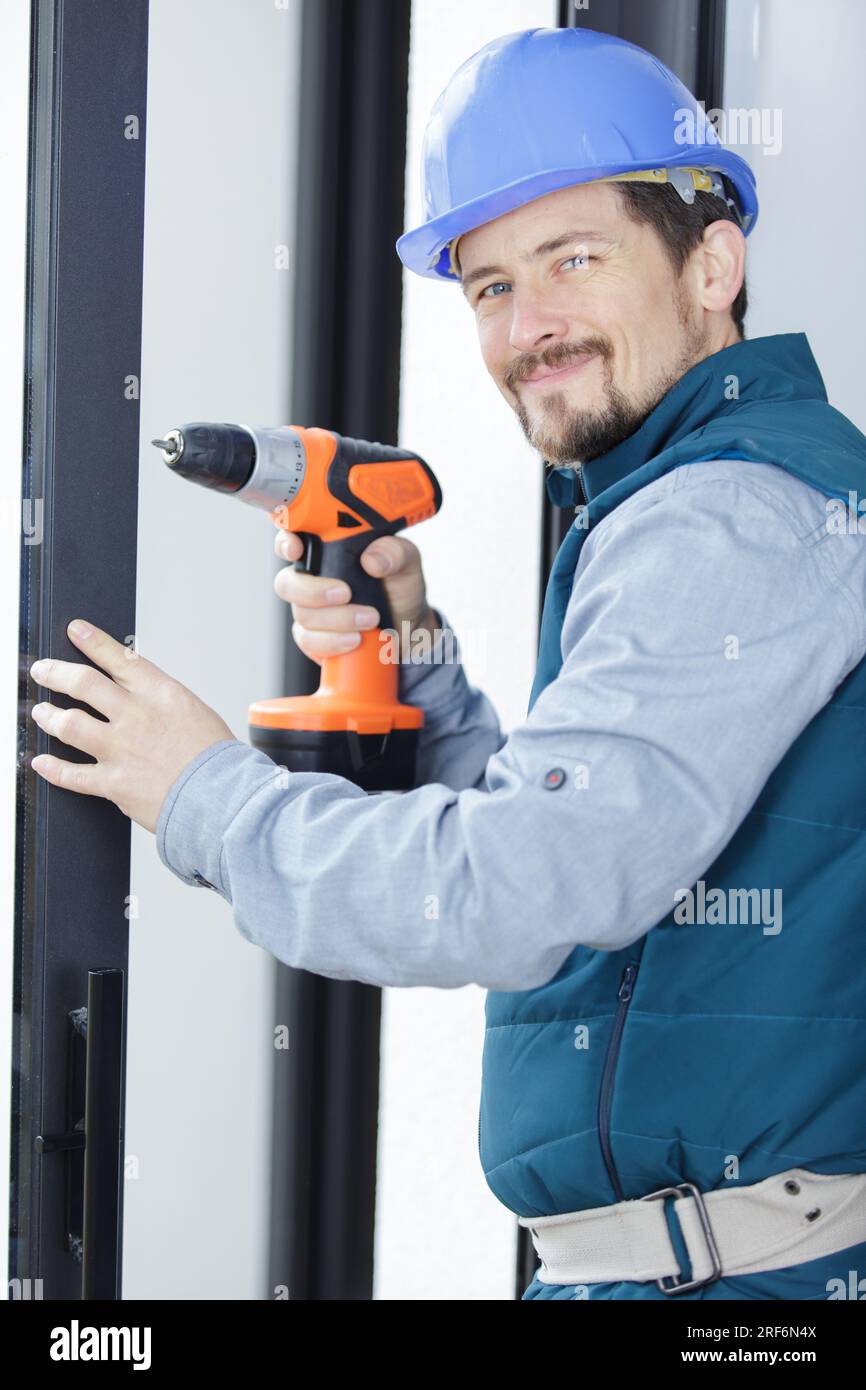 smiling worker fixing a window handle using a cordless screwdriver Stock Photo