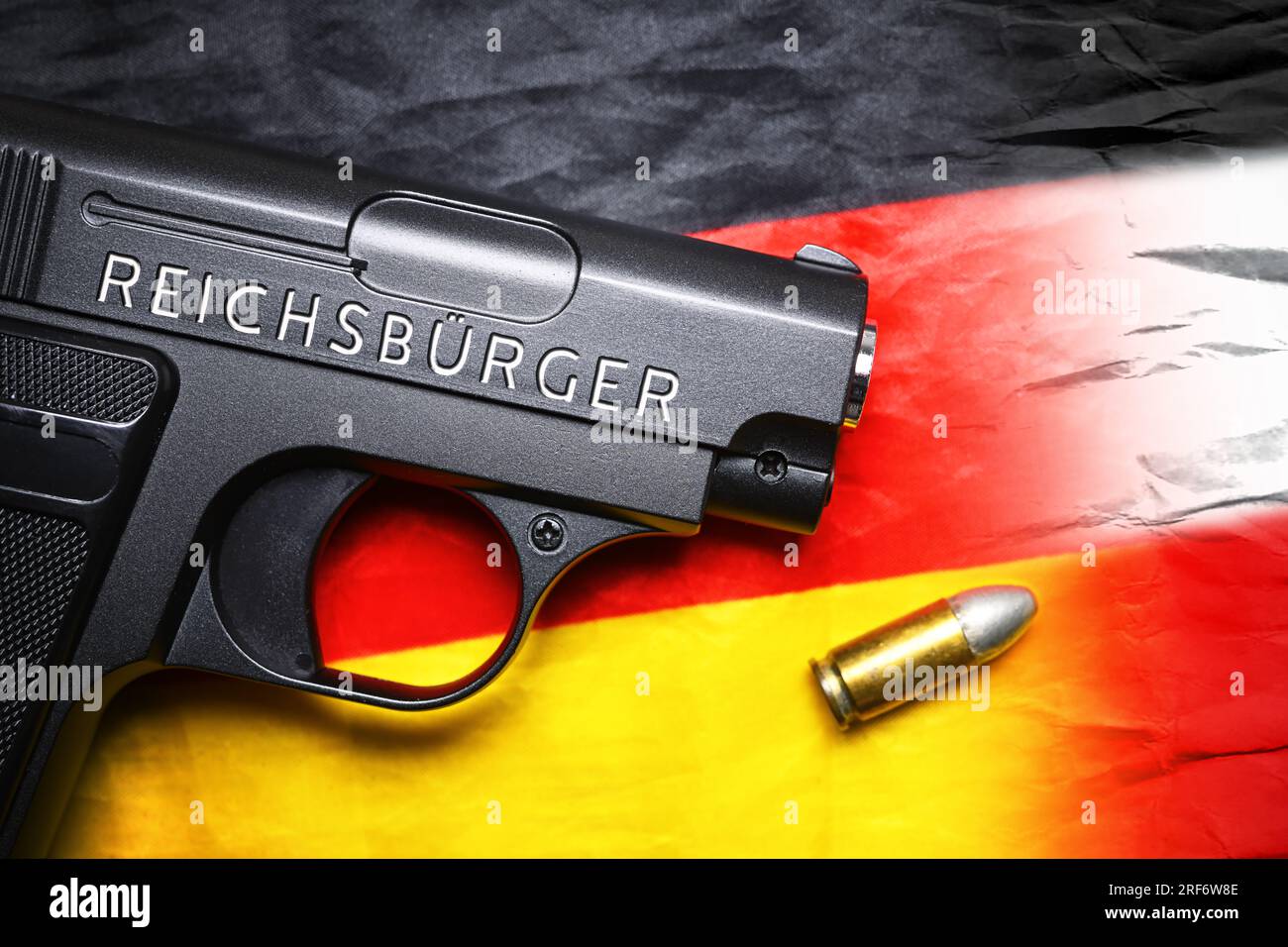 FOTOMONTAGE, Waffe mit Schriftzug Reichsbürger auf einer Deutschlandfahne Stock Photo