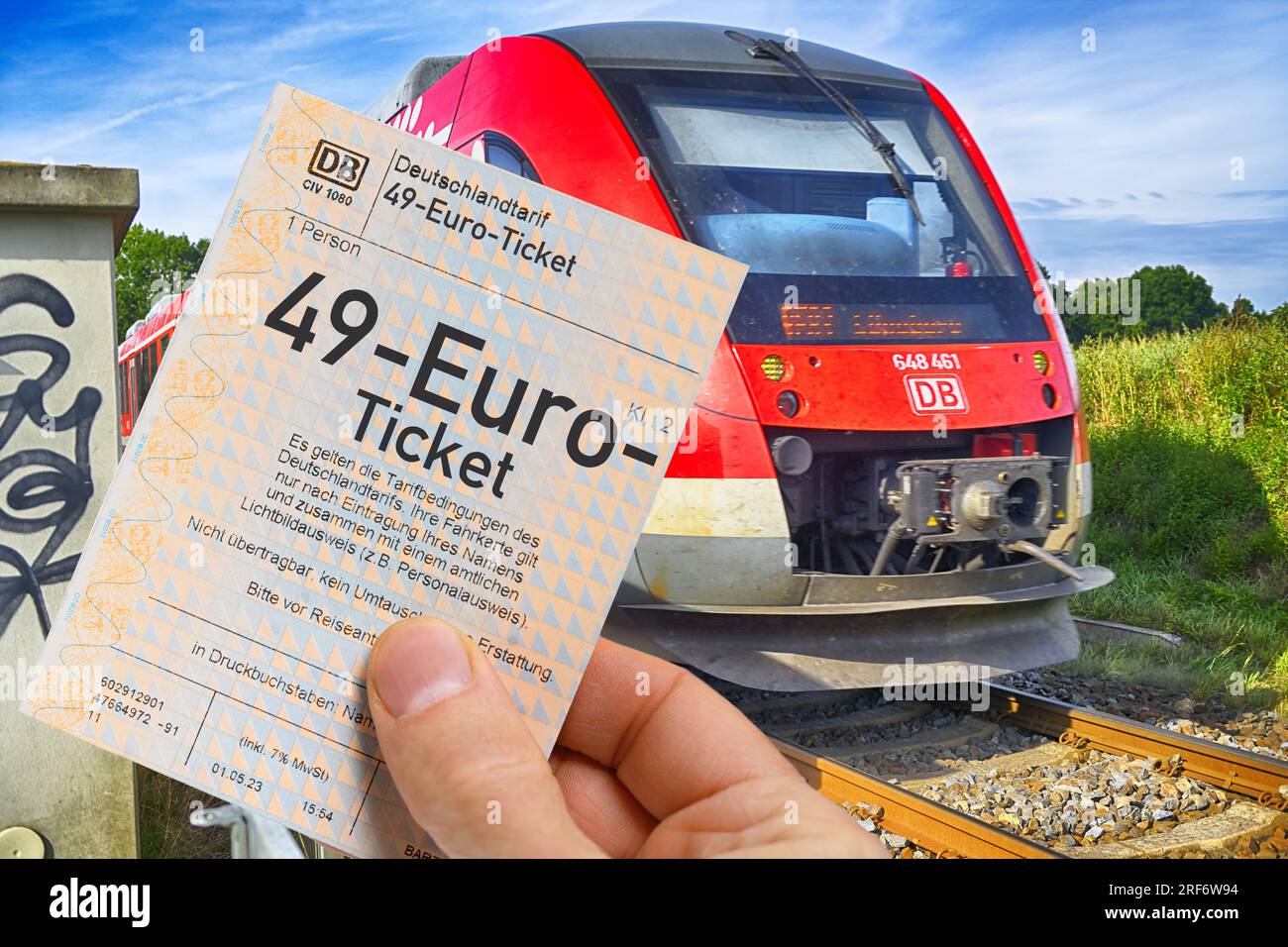 FOTOMONTAGE, Hand hält 49-Euro-Ticket vor Regionalbahn, Symbolfoto Stock Photo