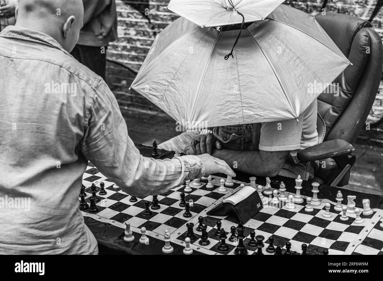 It may be raining, but the speedy chess game continues on Brick Lane in the rain in London. Stock Photo