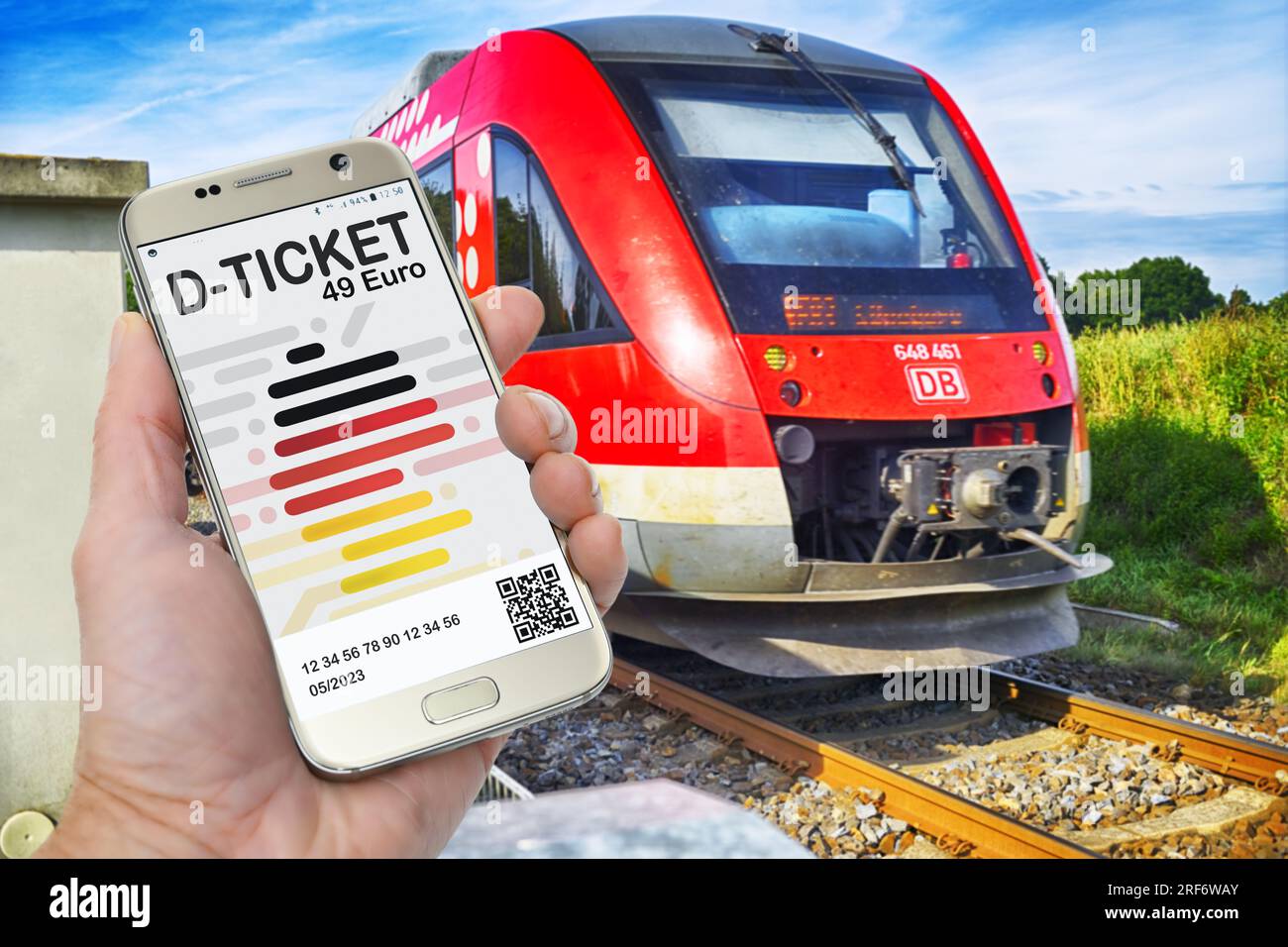 FOTOMONTAGE, Hand hält ein Smartphone mit D-Ticket vor einer Regionalbahn Stock Photo
