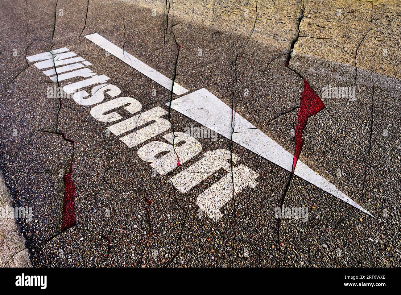FOTOMONTAGE, Absteigendes Pfeilsymbol auf Straßenasphalt und Schriftzug Wirtschaft, Symbolfoto Wirtschaftskrise Stock Photo