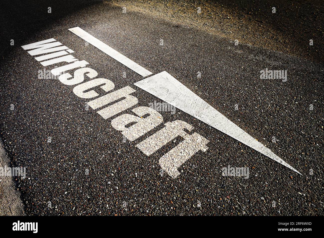 FOTOMONTAGE, Absteigendes Pfeilsymbol auf Straßenasphalt und Schriftzug Wirtschaft, Symbolfoto Wirtschaftskrise Stock Photo
