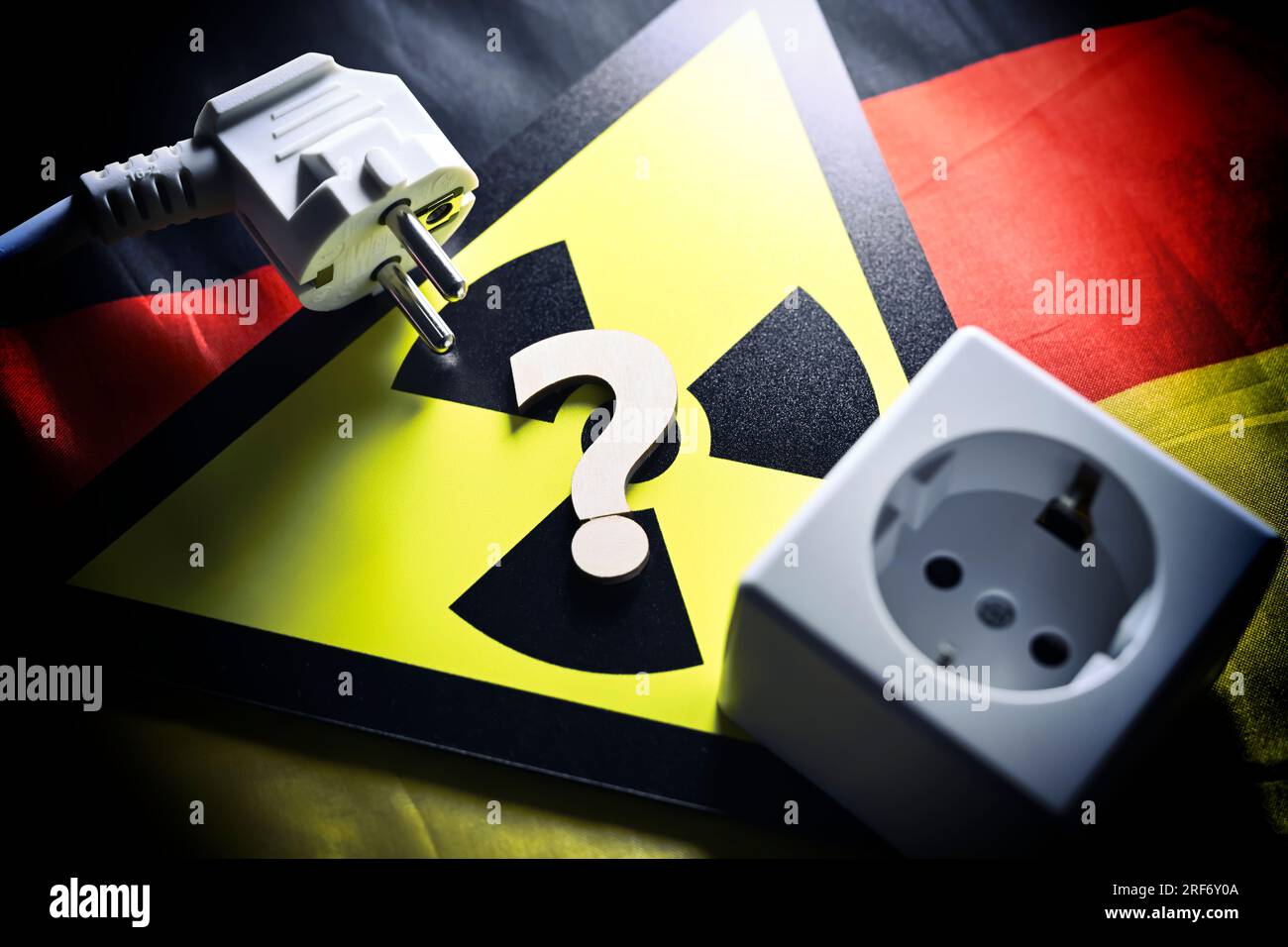 Schild mit Radioaktivitätssymbol und Fragezeichen, Steckdose und Stecker auf Deutschlandfahne, Symbolfoto für AKW-Abschaltung Stock Photo