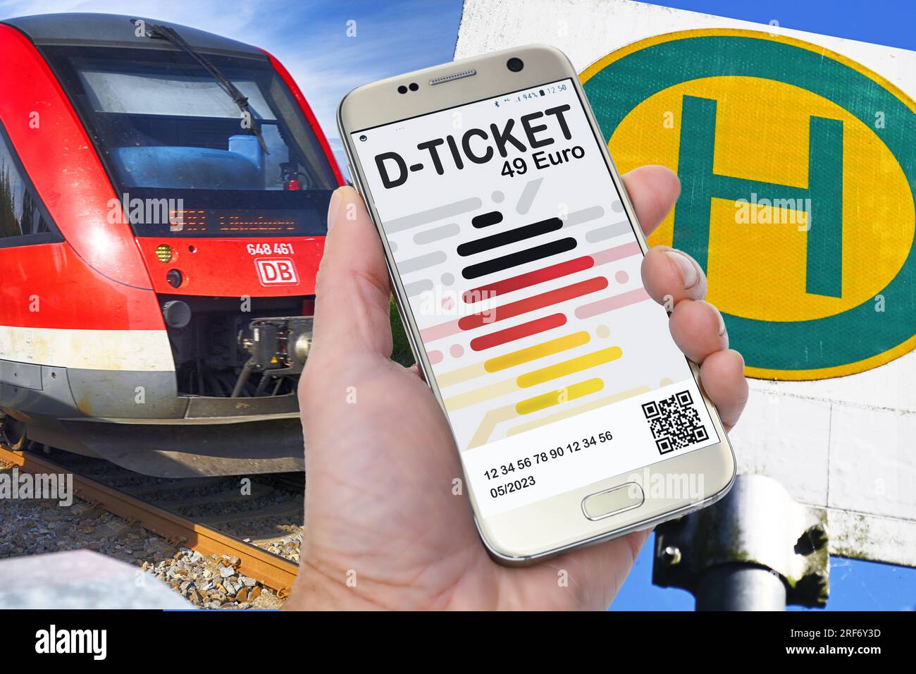 FOTOMONTAGE, Hand hält ein Smartphone mit D-Ticket vor einer Regionalbahn und einem Bushaltestellenschild Stock Photo